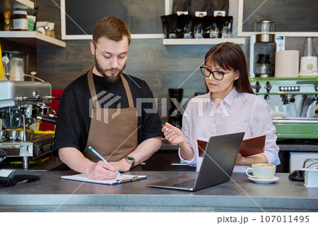Team male and woman talking, working, using laptop, coffee shop 107011495