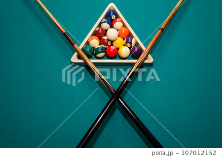 Billiard accessories balls and crossed cues on a billiard table Billiard accessories balls and crossed cues on a billiard table 107012152