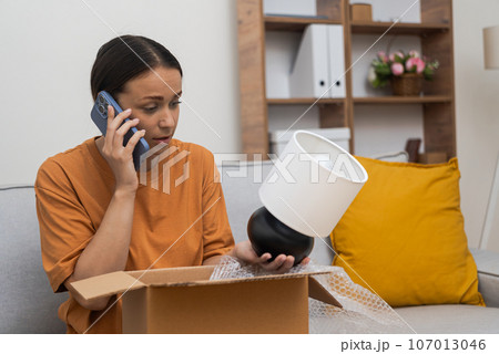 Confused woman receive wrong package, disappointment reaction, talking with customer support about return Confused woman receive wrong package, disappointment reaction, talking with customer support about return 107013046