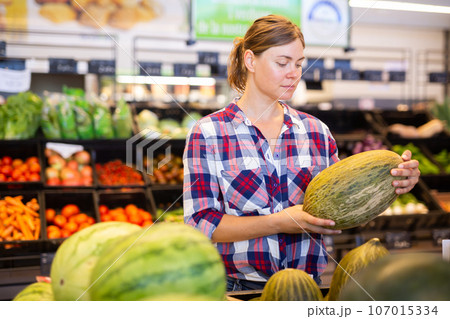 Young woman choosing ripe melon on counter at farmers market Young woman choosing ripe melon on counter at farmers market 107015334
