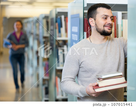 Portrait of a student guy in the library near the bookshelves Portrait of a student guy in the library near the bookshelves 107015441