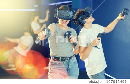Young guy and girl in vr headset stand shoulder to shoulder interacting with digital interface 107015491