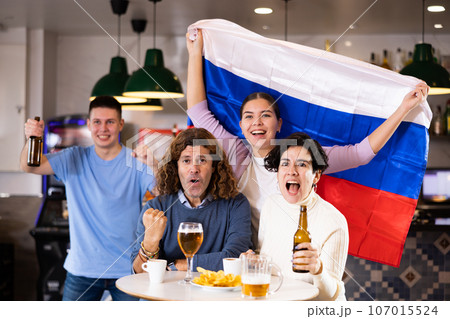 Happy friends of different ages drinking beer and celebrating the victory of the Russian team in night bar 107015524
