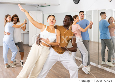 Woman and man practicing modern dance moves in pair during group class 107015734