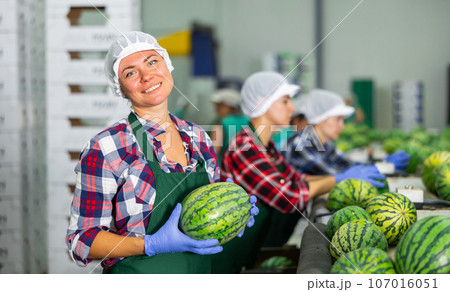 Portrait of positive woman fruit factory worker with watermelon 107016051