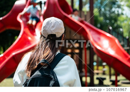 公園で遊ぶ子供を見守る母親 107016967