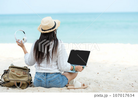 Lifestyle freelance woman listen music after using laptop working and relax on the beach. Lifestyle freelance woman listen music after using laptop working and relax on the beach. 107017634