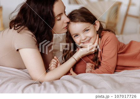 mother little daughter Happy mother kisses little girl daughter lying...の写真素材 [107017726] - PIXTA