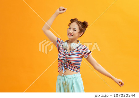Cheerful upbeat asian girl with headphones around neck, jumping from happiness or anticipation 107020544