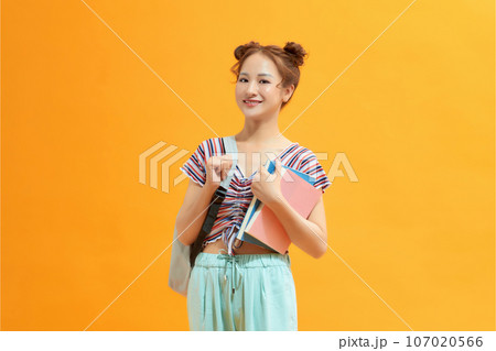 Portrait of a happy young asian female student on yellow background. Portrait of a happy young asian female student on yellow background. 107020566