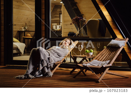 Woman wrapped in plaid fall asleep on terrace of tiny house in the evening Woman wrapped in plaid fall asleep on terrace of tiny house in the evening 107023183