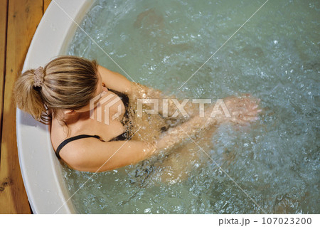 Overhead view of a woman sitting in jacuzziwith arms fold on her knees Overhead view of a woman sitting in jacuzziwith arms fold on her knees 107023200