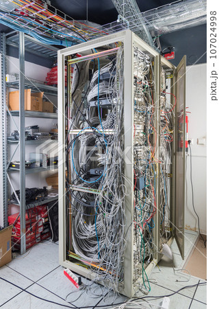server room rack with tangled network cables creating messy untidy network system 107024998