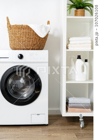 Laundry room with washing machine and basket with laundry 107026108