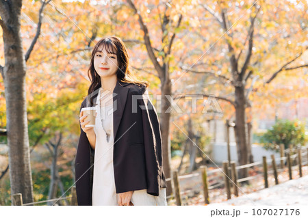 紅葉の季節に屋外でコーヒーを飲む女性 紅葉の季節に屋外でコーヒーを飲む女性 107027176