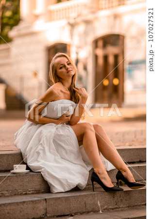 Woman city blanket. Morning in the big city. A blonde woman in a white blanket is enjoying in the city center. Photographed for social media Woman city blanket. Morning in the big city. A blonde woman in a white blanket is enjoying in the city center. Photographed for social media 107027521
