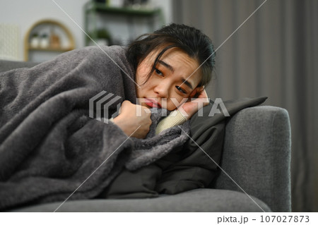 Sick mature woman wrapped blanket lying on couch, suffering high fever or seasonal flu. Health care concept Sick mature woman wrapped blanket lying on couch, suffering high fever or seasonal flu. Health care concept 107027873