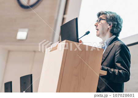 Speaker giving talk on podium at Business Conference. Business and Entrepreneurship. Expert presenting his work in lectures hall. Speaker giving talk on podium at Business Conference. Business and Entrepreneurship. Expert presenting his work in lectures hall. 107028601