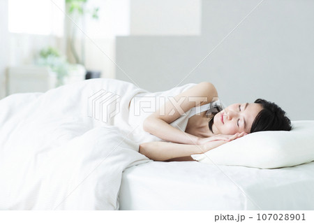 ベッドで寝る若い女性 107028901