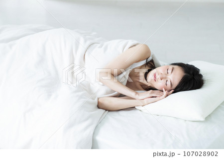 ベッドで寝る若い女性 107028902