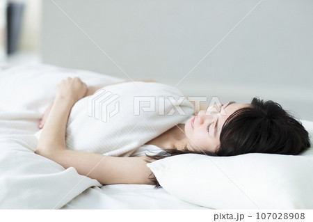 ベッドで寝る若い女性 107028908