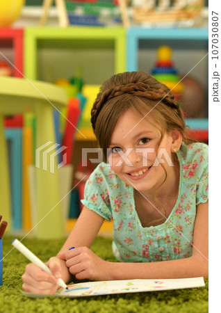 girl in the nursery draws lying on the carpet. 107030807