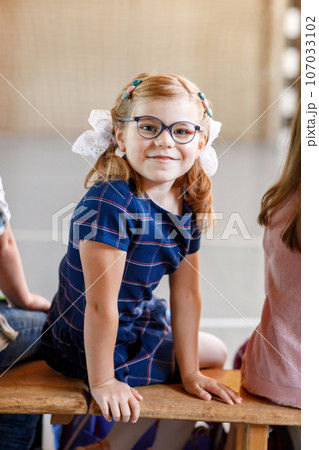 Children watching theater or concert at school. Little school girl smiling. Kids from back, musical and theatrical performace. 107033102