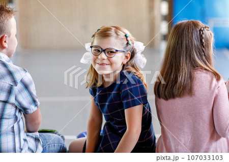 Children watching theater or concert at school. Little school girl smiling. Kids from back, musical and theatrical performace. 107033103