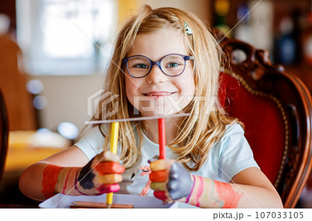 Little preschool girl painting with felt pens on hands. Creative cute child showing hands and arms painted with colorful pens or water colors. Laughing happy kid. 107033105