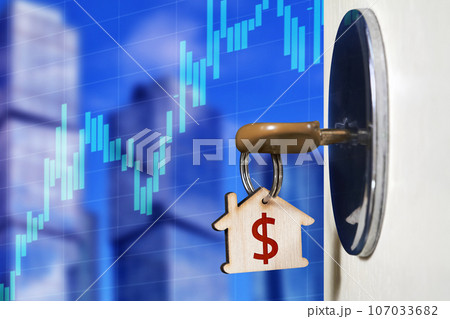 Key with a trinket in the form of a house in the door lock against urban development and a graph of the growth of real estate values Key with a trinket in the form of a house in the door lock against urban development and a graph of the growth of real estate values 107033682