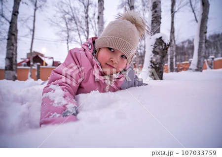 A girl plays in deep snow in the yard. 107033759