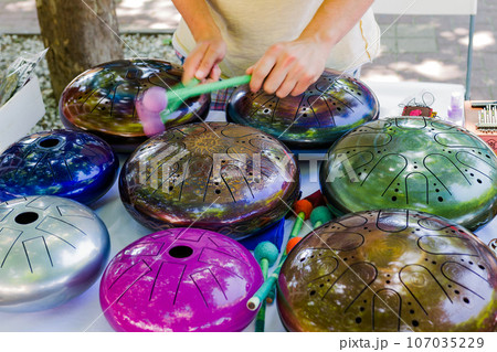 the musician plays colored hang drums, close-up the musician plays colored hang drums, close-up 107035229