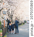 桜の下で記念撮影をする家族 107035869