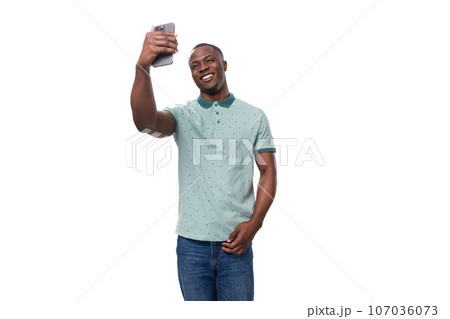 young slender American man dressed in a T-shirt and jeans makes a selfie on the phone young slender American man dressed in a T-shirt and jeans makes a selfie on the phone 107036073