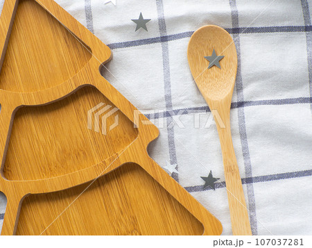 Empty christmas tree shaped wooden plate and spoon on towel background Empty christmas tree shaped wooden plate and spoon on towel background 107037281