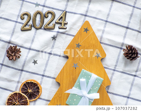 Empty christmas tree shaped wooden plate with 2024 on towel background 107037282
