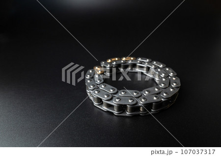 New timing chain of an internal combustion engine on a black background in selective focus. Spare parts new New timing chain of an internal combustion engine on a black background in selective focus. Spare parts new 107037317