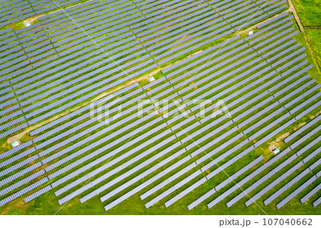 Aerial view of solar power plant on green field. Electric panels for producing clean ecologic energy. 107040662