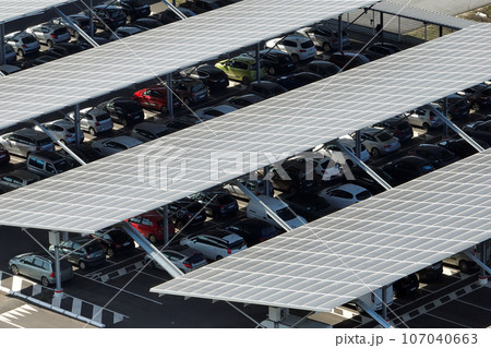 Aerial view of solar panels installed over parking lot with parked cars for effective generation of clean energy 107040663