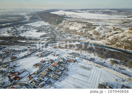 Aerial view of residential houses with snow covered roofops in suburban rural town area in winter Aerial view of residential houses with snow covered roofops in suburban rural town area in winter 107040688
