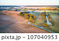 Warm sunny September morning. Autumn beautiful fog landscape. Small river curves in trees. Bright sunny misty riverside. Scenic view of rural sunrise. Village in Agriculture fields 107040953