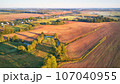Warm sunny September morning. Autumn beautiful fog landscape. Small river curves in trees. Bright sunny misty riverside. Scenic view of rural sunrise. Village in Agriculture fields. 107040955