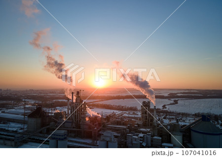 Aerial view of cement factory tower with high concrete plant structure at industrial production area at sunset. Manufacturing and global industry concept 107041016