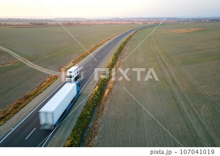 Aerial view of cargo trucks driving on highway hauling goods. Delivery transportation and logistics concept Aerial view of cargo trucks driving on highway hauling goods. Delivery transportation and logistics concept 107041019