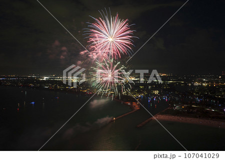 Aerial view of bright fireworks exploding with colorful lights over sea shore on US Independence day holiday Aerial view of bright fireworks exploding with colorful lights over sea shore on US Independence day holiday 107041029