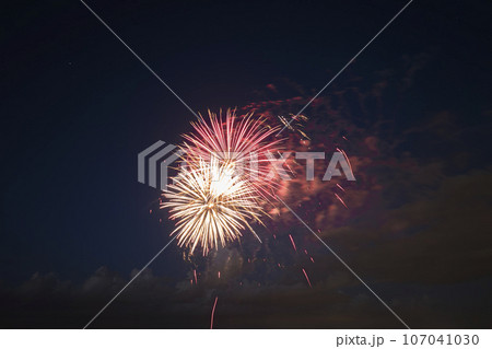 Aerial view of bright fireworks exploding with colorful lights against dark night sky on US Independence day holiday 107041030