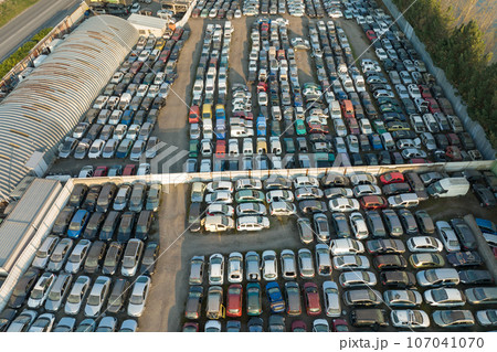 Aerial view of big parking lot of junkyard with rows of discarded broken cars. Recycling of old vehicles Aerial view of big parking lot of junkyard with rows of discarded broken cars. Recycling of old vehicles 107041070