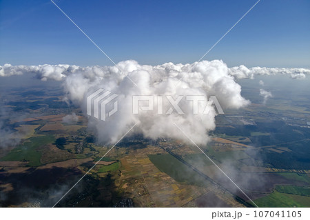 Aerial view from airplane window at high altitude of earth covered with white puffy cumulus clouds. 107041105