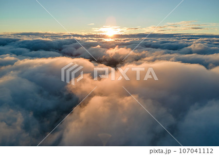 Aerial view from airplane window at high altitude of dense puffy cumulus clouds flying in evening 107041112