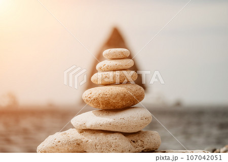 balanced rock pyramid on the pebbled beach is a study in harmony and balance. golden sea bokeh provide a stunning backdrop at sunset. Zen stones invite meditation and calm. spa or wellness concept. balanced rock pyramid on the pebbled beach is a study in harmony and balance. golden sea bokeh provide a stunning backdrop at sunset. Zen stones invite meditation and calm. spa or wellness concept. 107042051